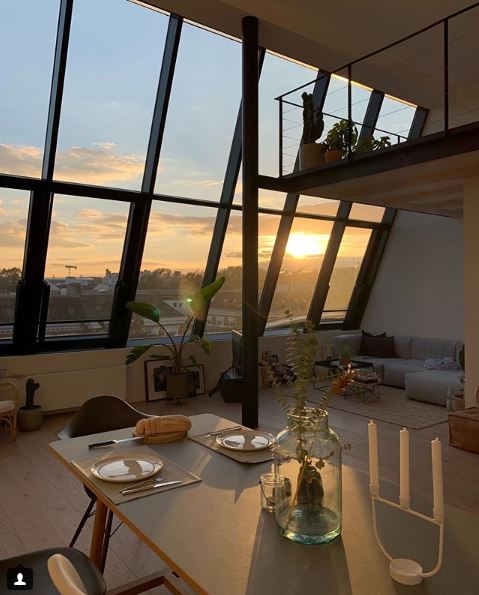 Wohnbereich mit Fensterfront bis zum Dach und Blick über die Dächer